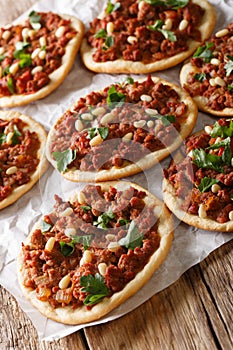 BeefÂ Sfiha Lebanese mini pizzas topped with ground beef, onions, tomato, and pine nuts closeup. vertical